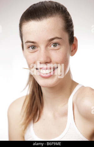 Teenager-Mädchen, Frau, mit einem Zahnstocher zwischen den Zähnen Stockfoto