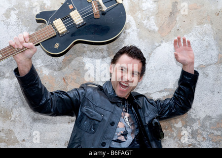 Junger Mann winken eine Gitarre in der Luft Stockfoto