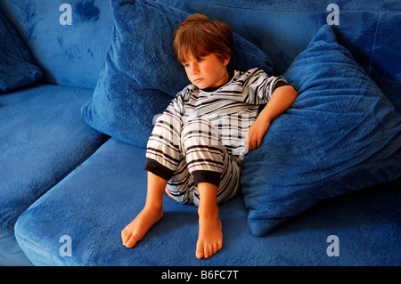 Kleiner Junge sitzt auf einem blauen Sofa vor dem Fernseher, in Illhaeusern, Elsass, Frankreich, Europa Stockfoto