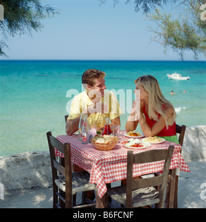 Griechenland, junge Paare, Essen und trinken im Freien in Taverne am Meer Stockfoto