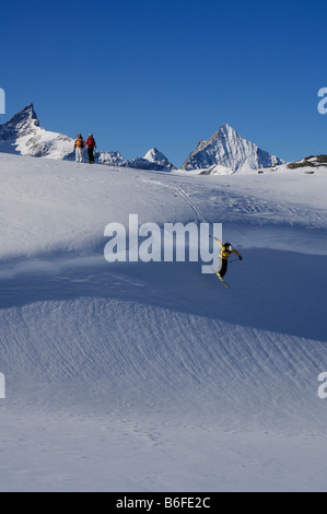 Backcountry Skifahrer, Freerider, springen einem Gesims auf Sandiger Boden Skigebiet vor dem Zinalrothorn und Obergabelhorn Stockfoto