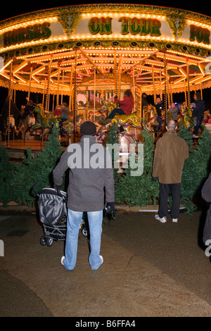 UK Cheshire Chester Zoo Frost Fair Kinder genießen Fahrt auf traditionelle Kirmes Karussell von Eltern beobachtet Stockfoto