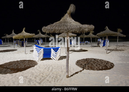 Sonnenschirme und gestapelten Liegestühle am Strand von Sa Coma bei Nacht, Mallorca, Balearische Inseln, Spanien, Europa Stockfoto