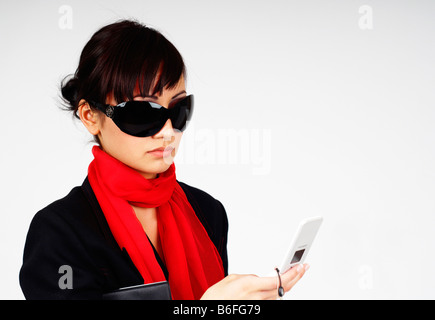 Junge Geschäftsfrau mit Sonnenbrille Wählen einer Nummer auf ihrem Handy Stockfoto