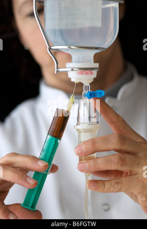 Arzt eine Infusion durch Einspritzen von Medizin in der Infusion vorbereiten Stockfoto