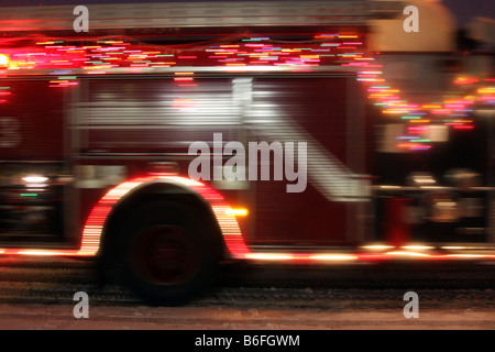 Die Unschärfe ein Feuerwehrauto alle dekoriert mit Weihnachtsbeleuchtung in einer Parade während eines Schneesturms Stockfoto