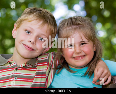 Ein Mädchen, vier Jahre alt, und ein Junge, sechs Jahre alt, arm in arm Stockfoto
