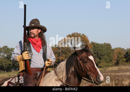 Ein Cowboy mit seinem Pferd und Gewehr auf der ranch Stockfoto