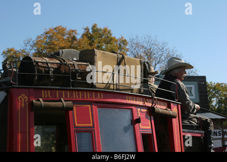 Zwei Cowboys, die einer alten Westernstadt Butterfield Overland Stage Coach durchfahren Stockfoto