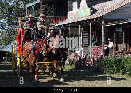 Zwei Cowboys, die einer alten Westernstadt Butterfield Overland Stage Coach durchfahren Stockfoto