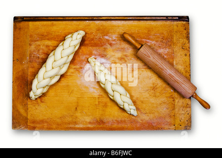 Geflochtene Brot oder geflochtenen Laib, ungebrannten, auf ein Backblech neben einem Nudelholz Stockfoto