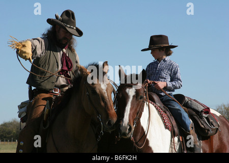 Ein Cowboy Vater seinen Sohn zeigt, wie man eine Kuh auf der Ranch Seil Stockfoto