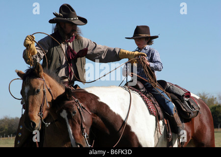 Ein Cowboy Vater seinen Sohn zeigt, wie man eine Kuh auf der Ranch Seil Stockfoto