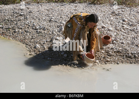 Eine Native American Indian Frau füllen Töpfe voll Wasser aus dem Bach Stockfoto