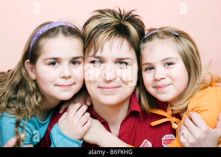 Lächelnde Mutter, 36 Jahre alt, mit ihren beiden Töchtern, 10 und 6 Jahre alt, im Innenbereich Stockfoto