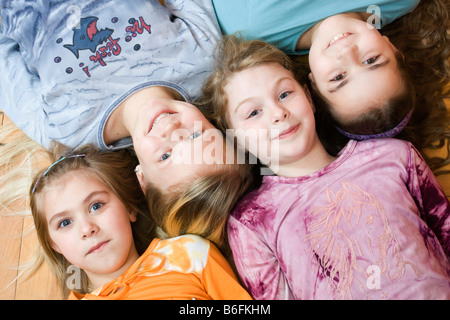 Gruppe von vier kleine Mädchen liegt auf dem Boden, von der linken Seite 6, 11, 9 und 10 Jahre alt, aus der Vogelperspektive Stockfoto