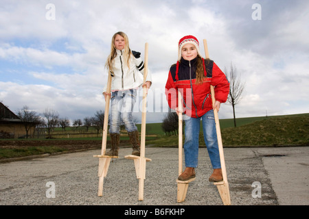 Mädchen, 11 und 10 Jahre alt, auf Stelzen, außerhalb Stockfoto