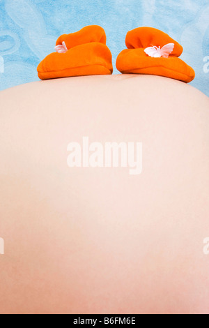 Bauch der schwangeren Frau mit Baby booties Stockfoto