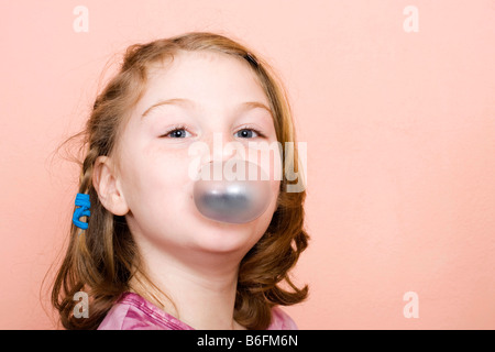 Kleines Mädchen, 9 Jahre, mit Kaugummi-Blase Stockfoto