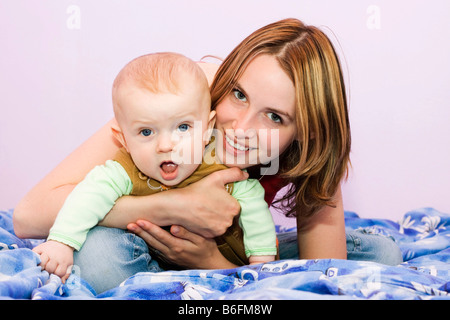 Lächelnde junge Mutter, 25 Jahre alt, und ihr Sohn, 7 Monate alt Stockfoto