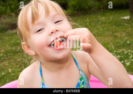 Lächelnde blonde Mädchen, 4 Jahre, Essen Kirsche Stockfoto