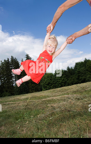 Blonde Mädchen wird geschwungen, 2 Jahre alt, außerhalb Stockfoto