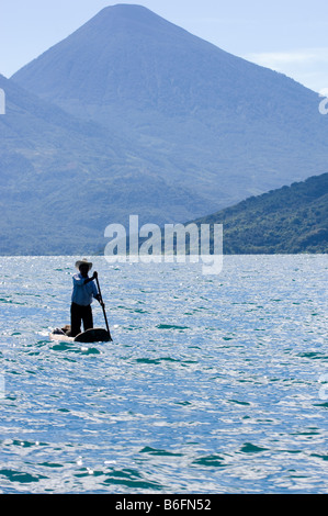 Lago de Atitlan. Guatemala. Traditionellen Fischer in seinem kleinen Boot beim Rudern stehend. Volcan San Pedro auf Hintergrund. Stockfoto