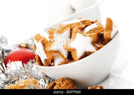 Aromatisierte sternförmige Zimtgebäck in eine weiße Schüssel und Weihnachtsdekorationen Stockfoto