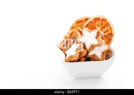 Sternförmige Zimtgebäck mit getrockneten Orangenscheiben in eine Schüssel geben Stockfoto