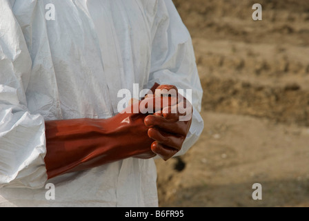 Körpersprache, ein Mann in einem Schutzanzug, der Schutzhandschuhe trägt, was einen Umstand erklärt Stockfoto