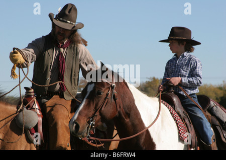 Ein Cowboy Vater seinen Sohn zeigt, wie man eine Kuh auf der Ranch Seil Stockfoto