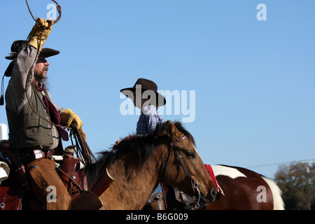 Ein Cowboy-Vater auf dem Pferderücken zeigt seinen Sohn wie ein Seil, um Vieh zu fangen zu werfen Stockfoto