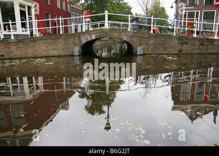 Fassaden-Vorderseite beherbergt alte kleine Steinbrücke in Delft "Bygata" über dem Wasser Kanal Wasserstraße reflektiert, Niederlande Stockfoto