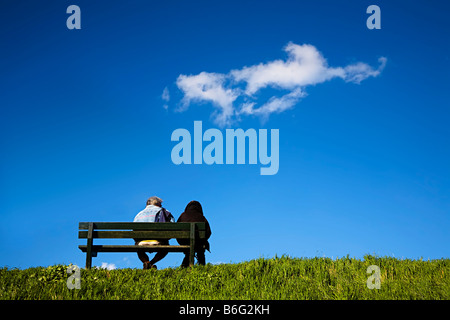 Zwei Menschen sitzen auf der Bank am Deich Niederlande Stockfoto