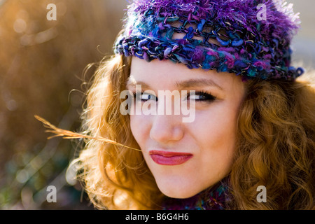 Kaukasische Frau lila stricken Hut trägt, Rasen-Zweig in Mund - USA Stockfoto