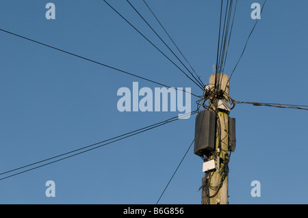 Telefonleitungen, die strahlenförmig von der Spitze des einen Telegrafenmast vor blauem Himmel, UK Stockfoto