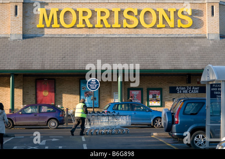 ein Mann treibt eine Gruppe von shopping Trolleys außerhalb Morrisons Supermarkt Shop speichern ABERYSTWYTH Wales UK Stockfoto