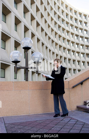 Kaukasische Geschäftsfrau stehen neben Bürogebäude lesen Zeitung Stockfoto