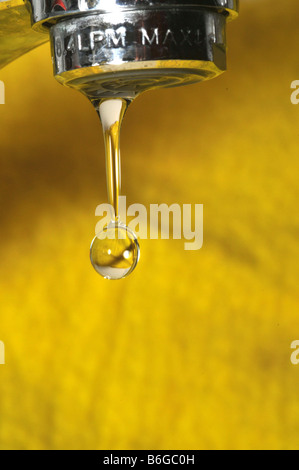 Wasser tropft aus einem Wasserhahn auf gelbem Hintergrund Stockfoto