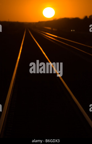 Eine helle orange Sonne über eine Eisenbahn-Hauptstrecke in westlichen Iowa. Stockfoto