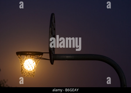 Der Vollmond steigt durch einen Basketballkorb in einem kleinen Stadtpark. Stockfoto