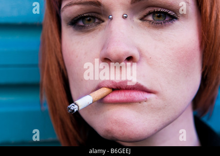 Junge rote Haare blass gehäutet Irin Frau mit einer Zigarette in ihrem Mund aussehende schwüle launisch starrte vor UK Stockfoto