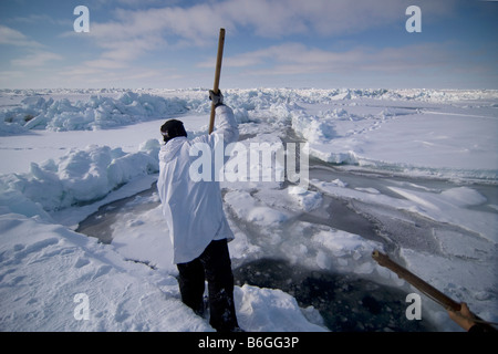 Inupiaq Walfänger öffnet ein Loch in das Packeis für potentielle Tierwelt Tschuktschensee passieren Stockfoto