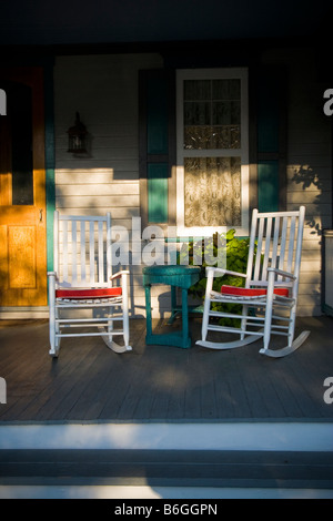 Abendsonne auf einem malerischen viktorianischen Veranda mit zwei Schaukelstühle und ein Fenster mit Gardinen. Stockfoto