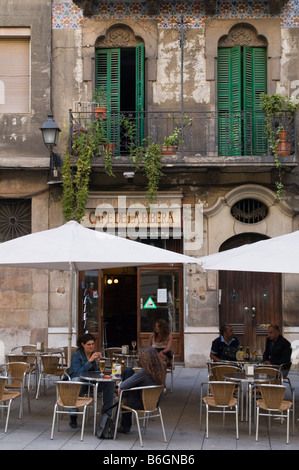 Eine verwitterte alte Gebäude und im Erdgeschoss ein Café, wo die Einheimischen genießen ein Getränk am Nachmittag in der Plaça de les Olles, La Ribera, Barcelona, Spanien Stockfoto