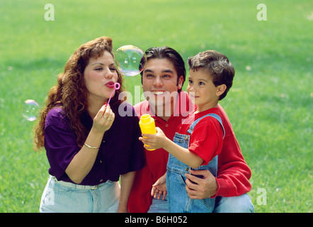 Latino oder hispanischen Familie, Mutter, Vater und Sohn Seifenblasen auf einer Wiese in einem park Stockfoto