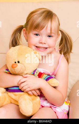 Lächelnde blonde Mädchen 4 Jahre mit Plüschtier Bär Stockfoto