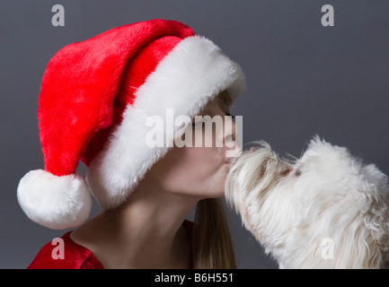 Kind trägt Weihnachtsmütze und küssen ihr Haustieren Hund Stockfoto