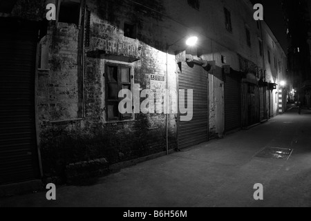 Ein altes leuchtet dunkel Gasse mit einer alten Lagerhalle im Schatten der obenliegenden Straßenlaternen in China geschlossen verschlossen Tür verblasst Ziegel Stockfoto