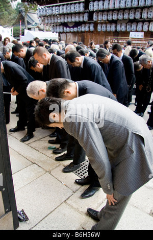 Eine Gruppe japanischer Geschäftsleute in Anzügen, Salarymen, die sich verbeugten und für Glück im Shinto Yasaka-Schrein in Kyoto zum Neujahr beteten Stockfoto